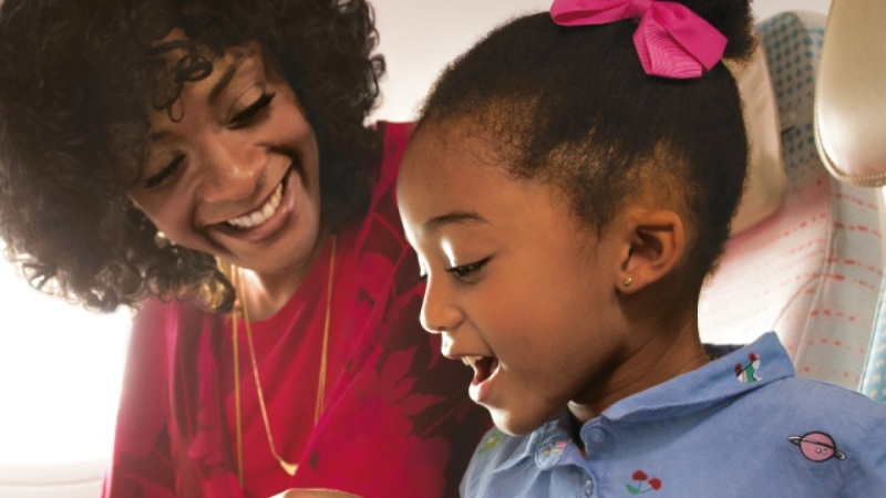 Mother and daughter smiling together on an airplane.