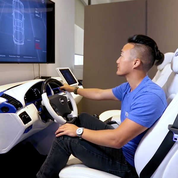 Young man sitting down in a demo car looking at screen.